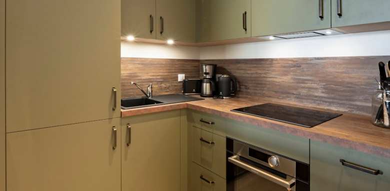 Rénovation complète cuisine en U revêtement tons bois et vert sauge