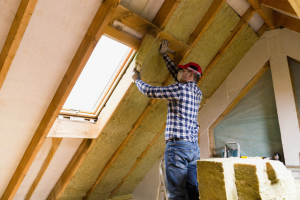 Travaux de rénovation énergétique avec isolation des combles sous toiture et pose d’isolant thermique autour d’une fenêtre de toit