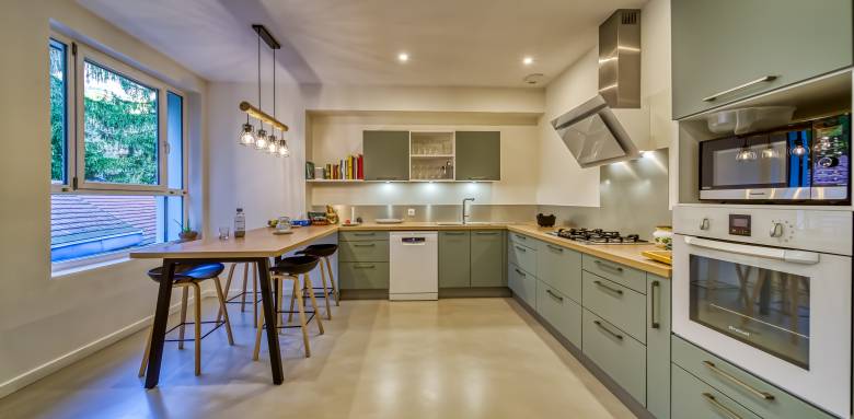 une cuisine bien éclairée : Des spots dans le plafond et un éclairage spécifique au-dessus de plan de travail, de la plaque de cuisson et de l'évier