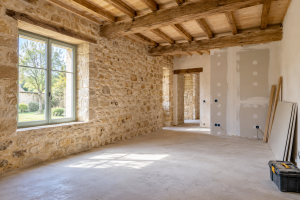 Intérieur d’une maison en pierre en cours de rénovation, avec poutres apparentes et cloisons en placo ».