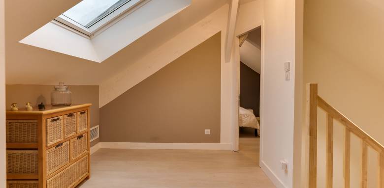 De meubles bas , un sol et des murs clairs dans ce dressing mansardé