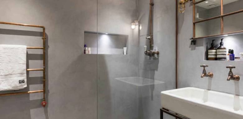 ambiance industrielle avec sèche serviette en tuyaux de cuivre et mur en béton brut