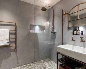 ambiance industrielle avec sèche serviette en tuyaux de cuivre et mur en béton brut