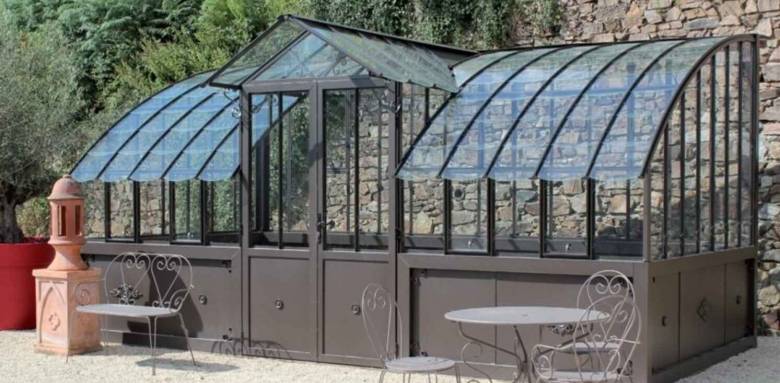 Verrière de jardin dos à un mur de pierr avec porte entrée