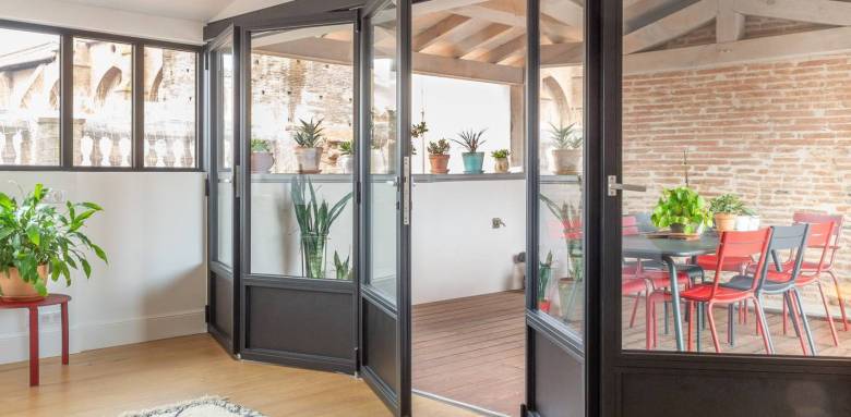 Bie vitrée repliable entre maison et véranda intérieur