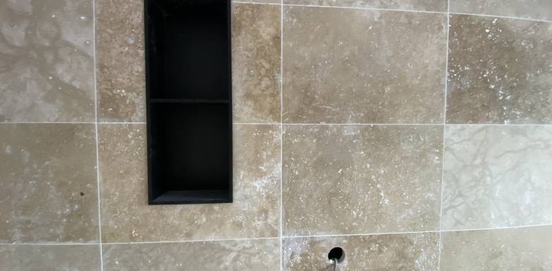 Rénovation d'une salle de bain, carrelage mural ton pierre et niche couleur profonde