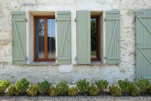 Volets PVC finition vert tilleul sur encadrement fenêtre finition bois chaud