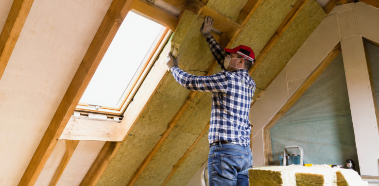 Travaux de rénovation énergétique avec isolation des combles sous toiture et pose d’isolant thermique autour d’une fenêtre de toit
