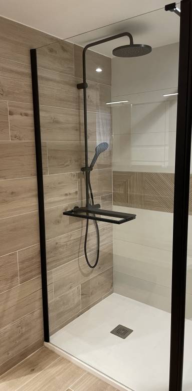 Carrelage imitation bois et robinetterie noire dans cette douche à receveur extra plat