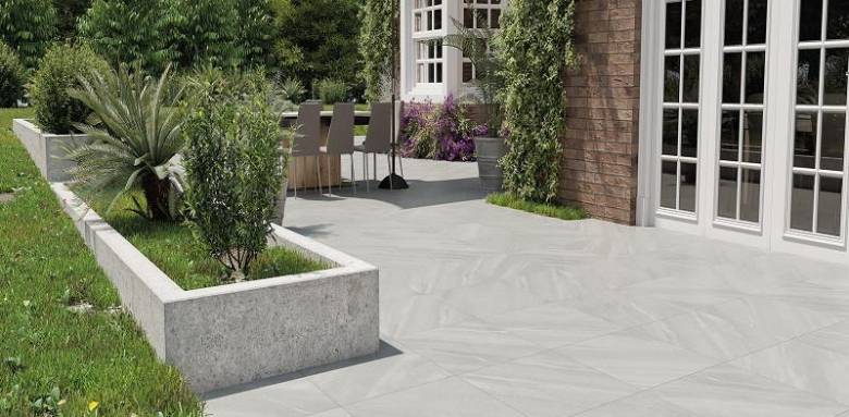 terrasse en carrelage extérieur grand format gris avec espace repas et jardin aménagé