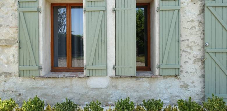 Volets PVC finition vert tilleul sur encadrement fenêtre finition bois chaud