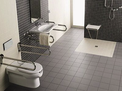 Douche de plain pied et WC avec poignée dans salle de bain PMR
