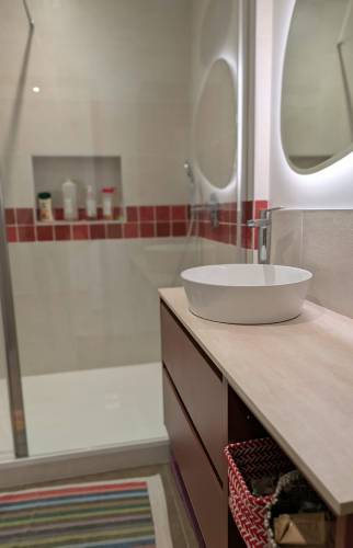 Détail du meuble vasque et du miroir rétroéclairé dans une salle de bain rénovée à Voiron.