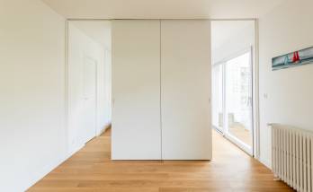 Porte cachée derrière une bibliothèque dans un salon moderne à Paris 16e.