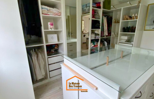 Dressing sur mesure avec îlot central vitré, rangements ouverts et penderies intégrées – aménagement intérieur en Haute-Savoie.