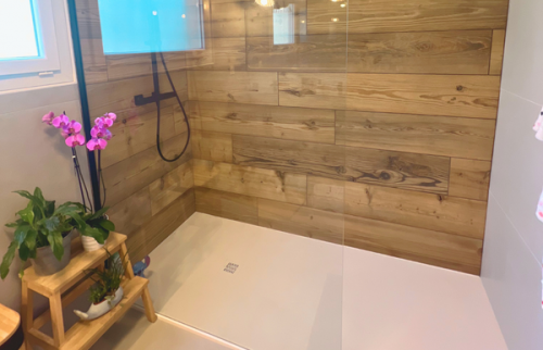 Détail de la douche moderne avec paroi vitrée et robinetterie noire.