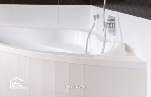 Salle de bain rénovée à Agen avec baignoire d’angle, WC suspendu et carrelage noir et blanc contemporain.