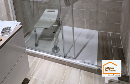 Vue détaillée de la douche sécurisée avec barre d’appui, mitigeur thermostatique et carrelage effet pierre dans une salle de bain rénovée à Aix-en-Provence.