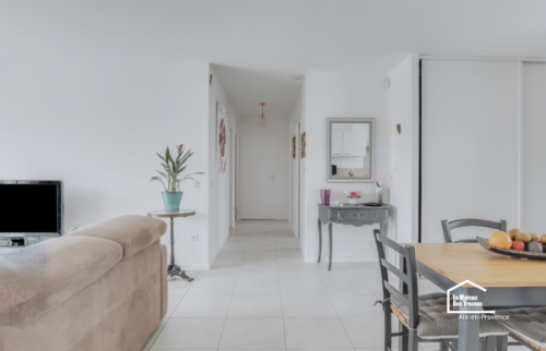 Cuisine rénovée à Aix-en-Provence avec mobilier blanc, plan de travail clair et aménagement fonctionnel ouvert sur la pièce de vie.