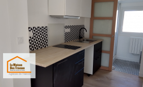 Rénovation de cuisine à Vesoul : Modernisation avec meubles noirs et blancs, crédence géométrique et plan de travail bois clair. Un projet signé La Maison Des Travaux Vesoul.