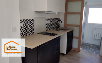 Rénovation de cuisine à Vesoul : Modernisation avec meubles noirs et blancs, crédence géométrique et plan de travail bois clair. Un projet signé La Maison Des Travaux Vesoul.