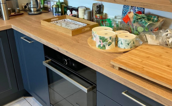 Cuisine moderne avec meubles bleu nuit, plan de travail en bois clair et étagères ouvertes avec accessoires déco.