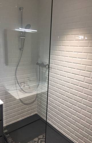 Douche rénovée avec carrelage métro blanc et colonne de douche moderne.