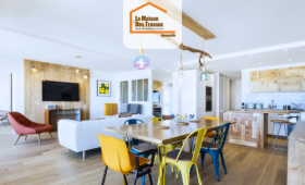 Pièce à vivre moderne en Haute-Savoie avec cuisine en bois clair, salle à manger colorée et salon ouvert – rénovation intérieure signée La Maison Des Travaux.