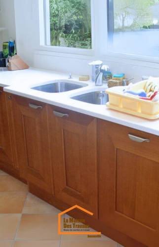 Evier double en inox dans une cuisine en U rénovée – plan de travail en résine blanche – vue extérieure sur jardin