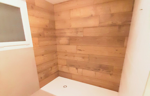 Espace douche avec carrelage imitation bois au veinage travaillé.