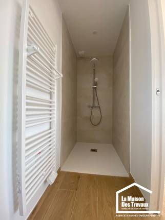 Douche avec receveur extra-plat et revêtement mural beige dans une salle d'eau rénovée à Damgan