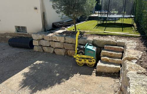 Compactage du sol et réalisation d’un escalier en pierre pour faciliter les accès entre les différents niveaux du terrain.
