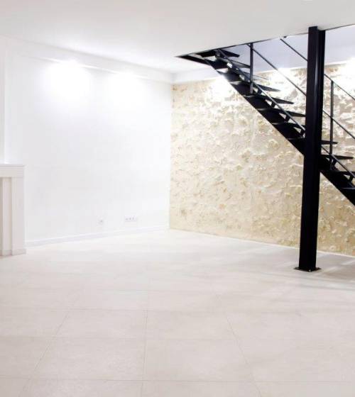 Pièce de vie, mur en pierre et escalier métallique