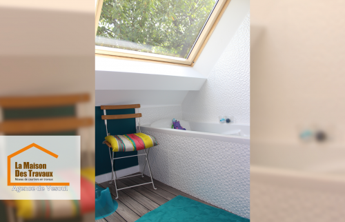 Salle de bain sous toit avec baignoire et puits de lumière - Espace optimisé à Saint-Loup-sur-Semouse avec carrelage texturé et vue extérieure verdoyante.