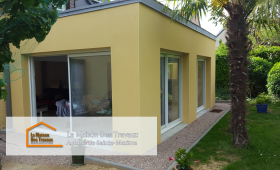 Vue intérieure de l'extension avec de grandes baies vitrées, baignant l’espace de lumière naturelle et offrant une vue apaisante sur le jardin.