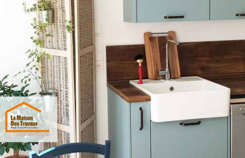 Rénovation de cuisine à Agen : Cuisine moderne avec façades bleu pastel, plan de travail en bois et évier farmhouse. Un projet signé La Maison Des Travaux Agen.