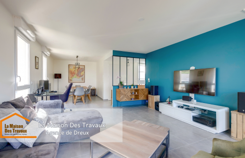 Un mur bleu turquoise contraste harmonieusement avec le reste de la pièce, offrant une touche de couleur à ce salon moderne.