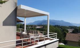 Vue extérieure de la pergola bioclimatique blanche, intégrée à la façade et aux garde-corps de la résidence.