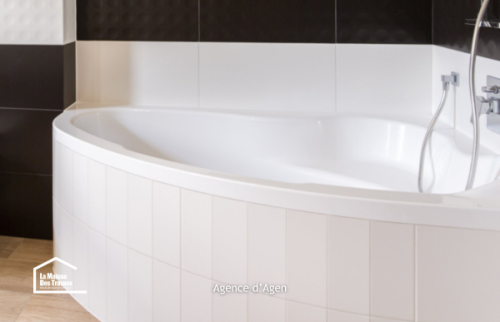 Détail d’une baignoire d’angle avec robinetterie moderne dans une salle de bain rénovée à Agen, Lot-et-Garonne.