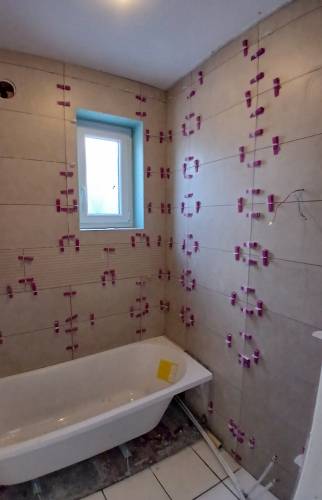 Pose du carrelage mural en cours dans la salle de bain à Courrières