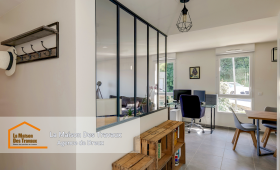 Une verrière élégante sépare l’entrée du salon, apportant une touche industrielle moderne et laissant entrer la lumière naturelle.