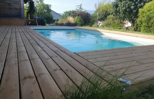 La nouvelle terrasse en bois offre un cadre chaleureux et confortable autour de la piscine.