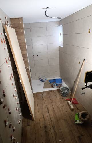 Chantier de rénovation complète d’une salle de bain ancienne à Charancieu avec pose du carrelage mural et du sol.
