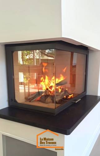 Gros plan sur un foyer vitré d’angle avec flammes actives et habillage noir – installation de cheminée à Bonneville en Haute-Savoie.