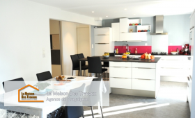 Vue d’ensemble de la cuisine rénovée avec un îlot central accueillant et une table à manger à proximité pour plus de convivialité.