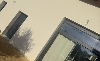 Façade rénovée avec enduit clair et menuiseries anthracite à Voiron