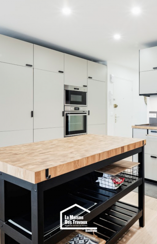 Cuisine équipée avec colonne intégrée pour four et micro-ondes, îlot central noir et bois, aménagement optimisé en Haute-Savoie.