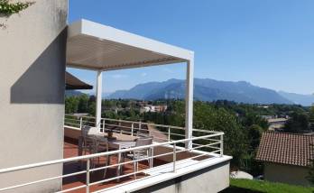 Vue extérieure de la pergola bioclimatique blanche, intégrée à la façade et aux garde-corps de la résidence.
