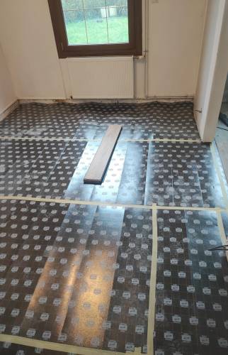 Préparation du sol avec pose d'une sous-couche isolante sur l'ancien carrelage.