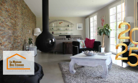 La photo met en avant un salon chaleureux et moderne, avec un poêle suspendu noir qui ajoute une touche contemporaine, et des ouvertures généreuses offrant une luminosité exceptionnelle 🌟.